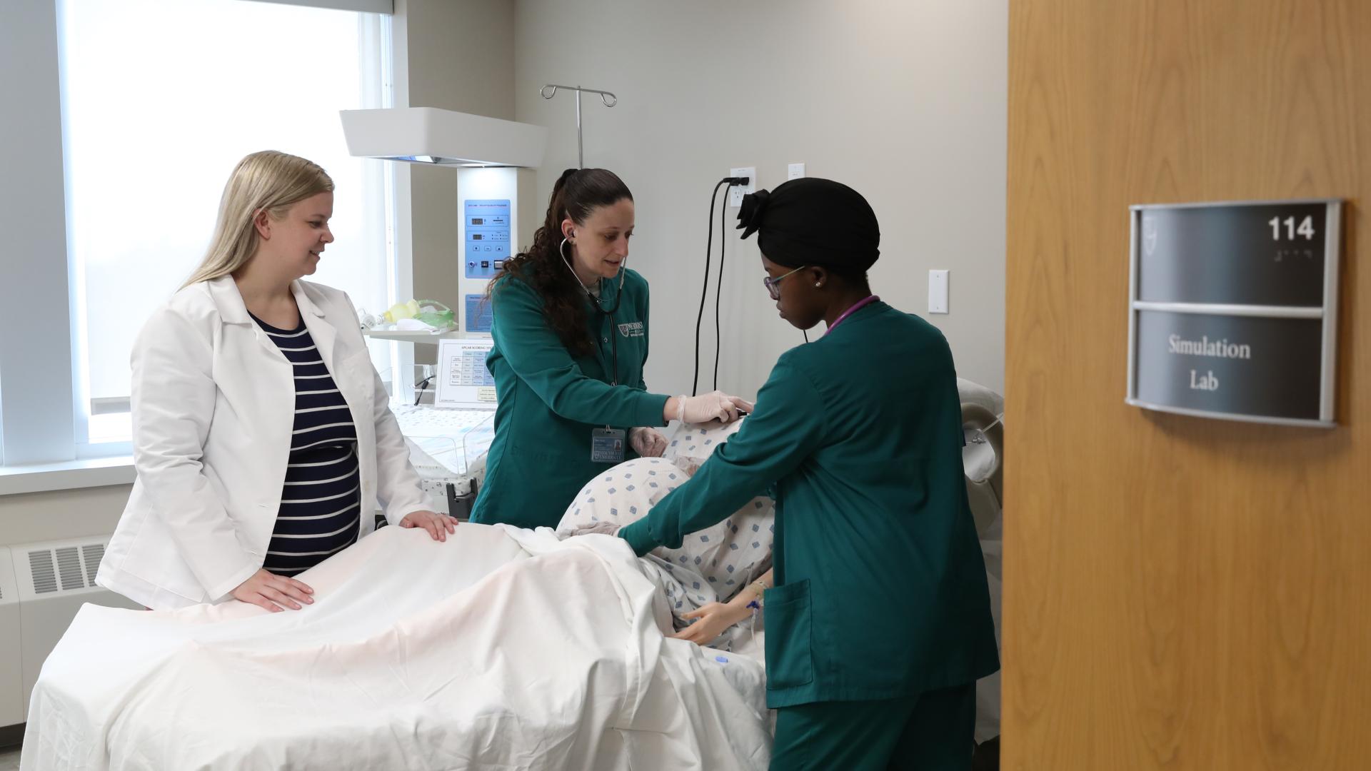 two female nursing Ƶapps and an instructor practice in a simulation lab